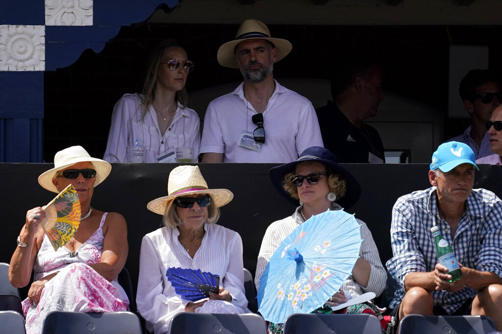Spectators protect themselves from the sun while watching the quarterfinal tennis match between Alejandro Davidovich Fokina of Spain and Botic van de Zandschulp of the Netherlands, at the Queen's Club Championships in London, Friday, June 17, 2022. (AP Photo/Alberto Pezzali)