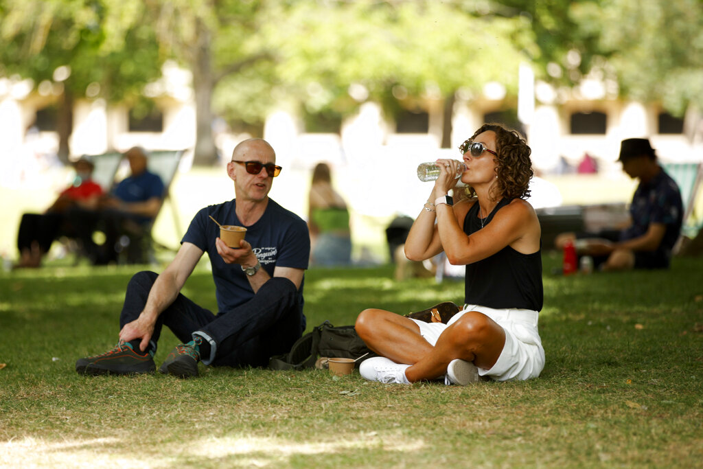 A man and woman picnic in the shade of a tree in hot weather in St James's Park in London, Thursday, June 16, 2022. Temperatures are forecast to reach 28 degrees Celsius, (82F), in London today as heat wave conditions continue.  (AP Photo/David Cliff)