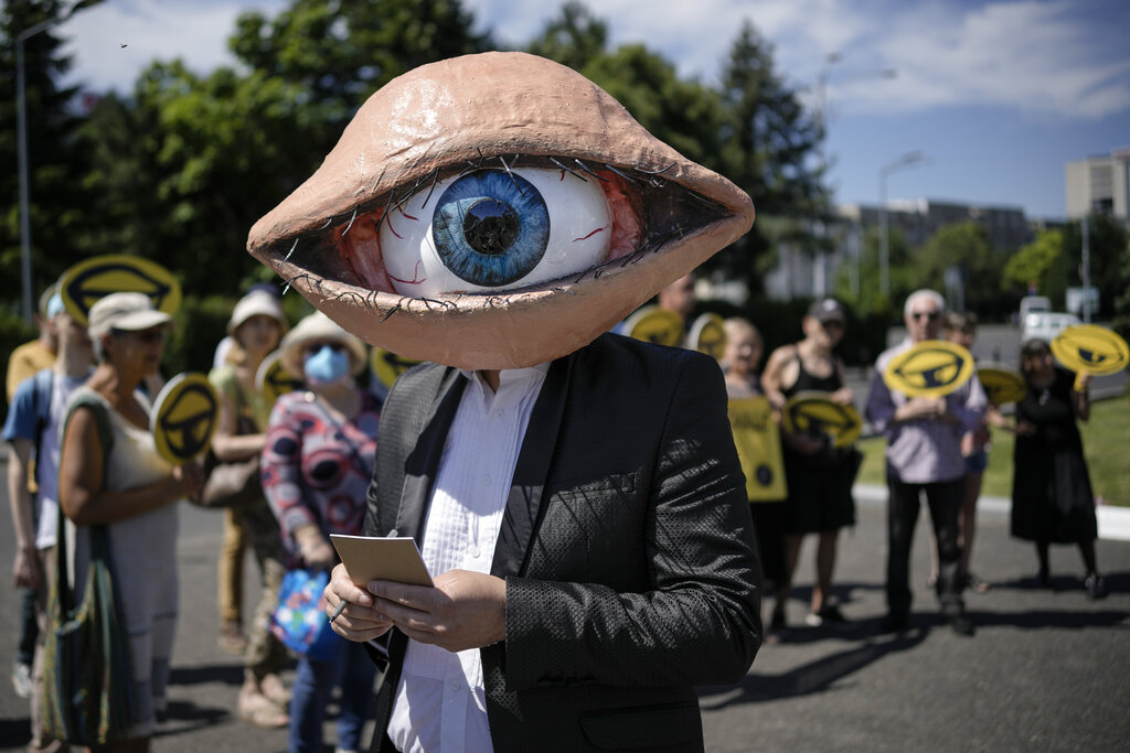 An activists wears a mask depicting a large eyeball during a protest against planned updates of the country's national security laws, after a draft was leaked to the media earlier this month, in Bucharest, Romania, Wednesday, June 22, 2022. Dozens of activists gathered outside the government headquarters to protest against proposed changes to the laws that offer increased power to Romania's intelligence service (SRI), which include an obligation for citizens and companies to offer support to the service if requested. (AP Photo/Vadim Ghirda)