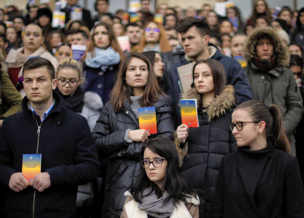 Romanian law students hold copies of the country's constitution during a silent protest outside the Faculty of Law building in Bucharest, Romania, Wednesday, Dec. 20, 2017. Romanian students staged a protest over planned modifications to the legal system they say will hamper prosecutions. (AP Photo/Vadim Ghirda)