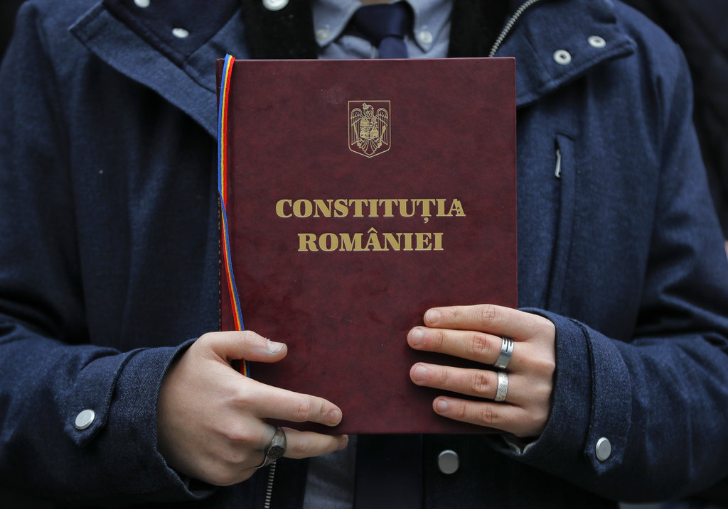 A Romanian law student holds a copy of the country's constitution during a silent protest outside the Faculty of Law building in Bucharest, Romania, Wednesday, Dec. 20, 2017. Romanian students staged a protest over planned modifications to the legal system they say will hamper prosecutions. (AP Photo/Vadim Ghirda)