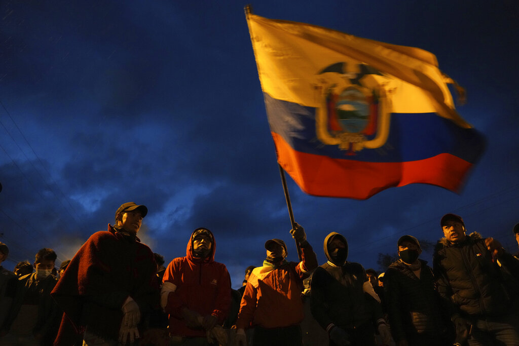 Indigenous protesters wave an Ecuadorian flag as they walk to Quito to protest in the capital against the economic policies of President Guillermo Lasso's government in Quito, Ecuador, Sunday, June 19, 2022. (AP Photo/Dolores Ochoa)