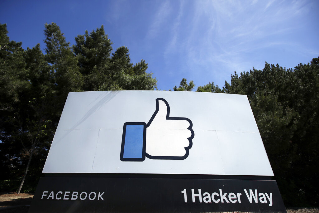 FILE - In this April 14, 2020 file photo, the thumbs up Like logo is shown on a sign at Facebook headquarters in Menlo Park, Calif. Social media and other internet companies face big fines in Britain if they don't limit the amount of harmful material such as child sexual abuse or terrorist content on their platforms, officials said Tuesday, Dec. 15, 2020. (AP Photo/Jeff Chiu, File)