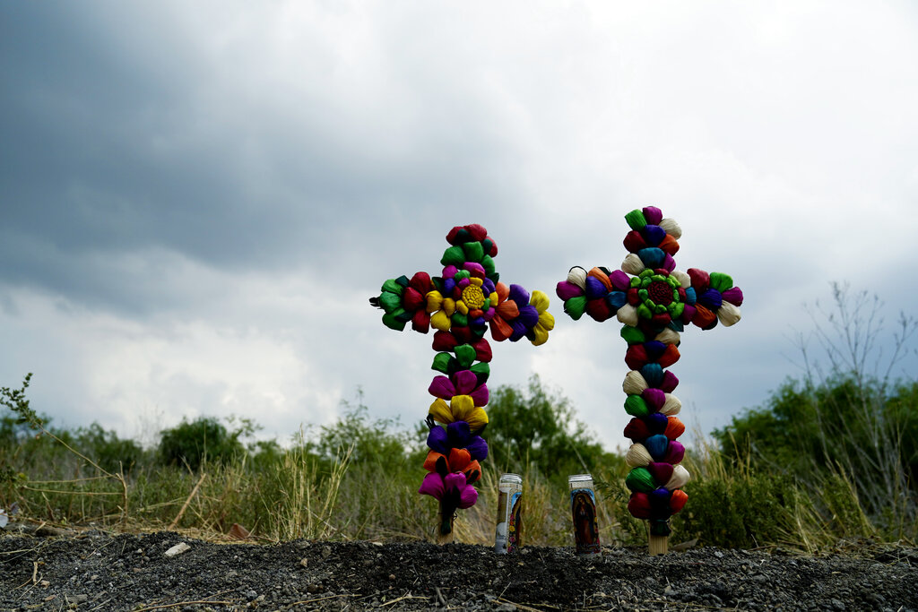 Crosses and candles stand as a make-shift memorial at the site where officials found dozens of people dead in an abandoned semitrailer containing suspected migrants, Tuesday, June 28, 2022, in San Antonio. (AP Photo/Eric Gay)