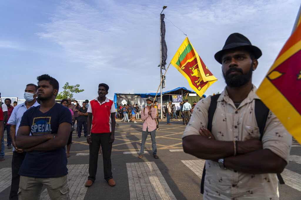 A protester holds a Sri Lanka flag at the site of a protest in Colombo in Colombo, Sri Lanka, Wednesday, July 13, 2022. The president of Sri Lanka fled the country early Wednesday, days after protesters stormed his home and office and the official residence of his prime minister amid a monthslong economic crisis that triggered severe shortages of food and fuel.(AP Photo/Rafiq Maqbool)