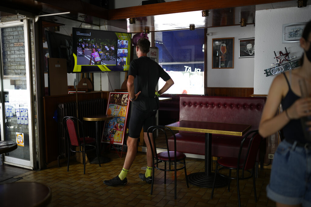 A cyclist watches live coverage in a bar in Vizille during the thirteenth stage of the Tour de France cycling race over 193 kilometers (119.9 miles) with start in Le Bourg d'Oisans and finish in Saint-Etienne, France, Friday, July 15, 2022. (AP Photo/Daniel Cole)