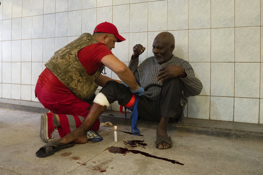A medical worker treats an injured man after Russian shelling at Barabashovo market in Kharkiv, Ukraine, Thursday, July 21, 2022. (AP Photo/Evgeniy Maloletka)
