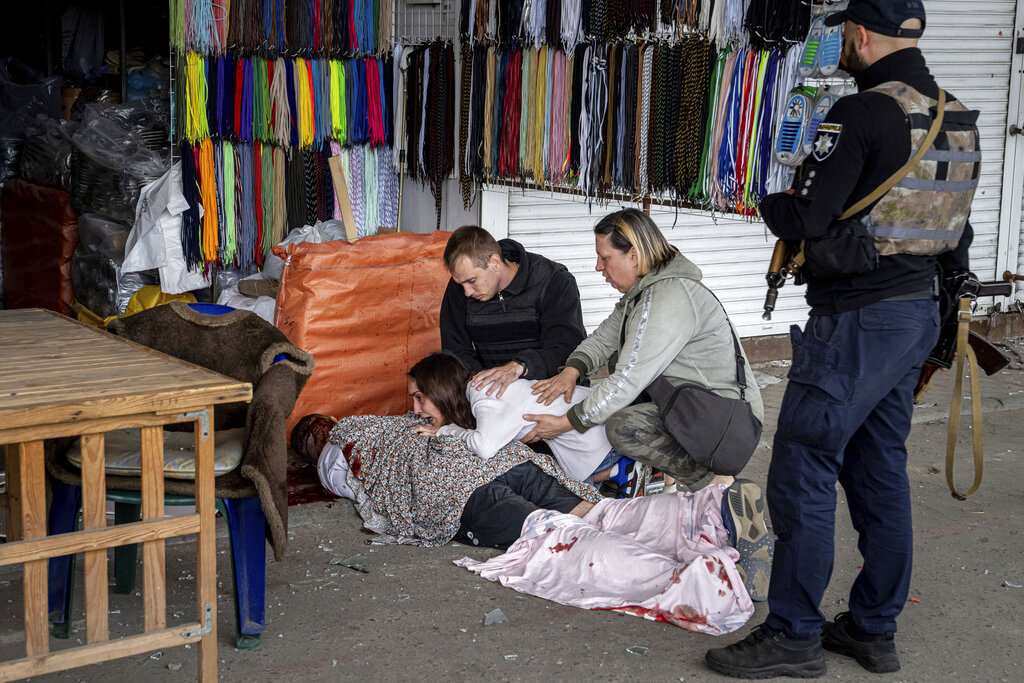 Sabina, centre, cries next to her killed husband Artem Pogorelets after Russian shelling at Barabashovo market in Kharkiv, Ukraine, Thursday, July 21, 2022. (AP Photo/Evgeniy Maloletka)