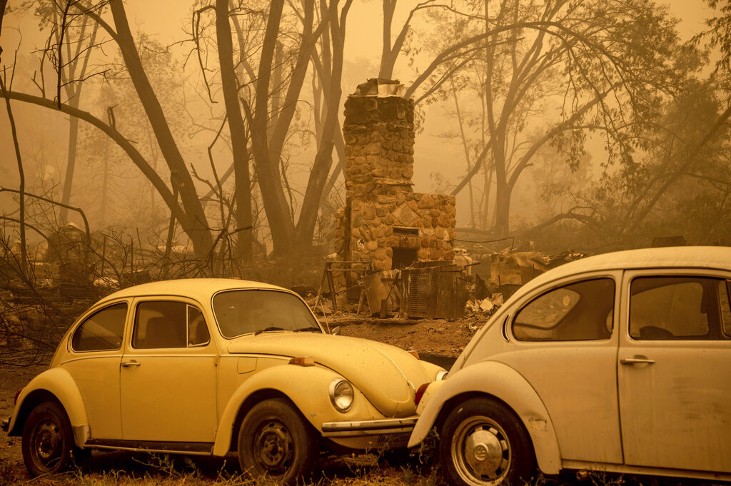 A chimney stands behind cars as the McKinney Fire burns in Klamath National Forest, Calif., on Sunday, July 31, 2022. (AP Photo/Noah Berger)