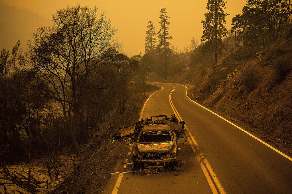 A scorched pickup truck rests on California Highway 96 in Klamath National Forest, Calif., as the McKinney Fire burns nearby, Saturday, July 30, 2022. (AP Photo/Noah Berger)