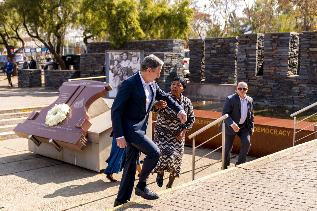 Secretary of State Antony Blinken and Antoinette Sithole, the sister of the late Hector Pieterson, speak together after laying a wreath at the Hector Pieterson Memorial in Soweto, South Africa, Sunday, Aug. 7, 2022. Peaceful child protesters were gunned down by police 30 years ago in an attack that awakened the world to the brutality of the apartheid regime. At top, is an iconic picture of Antoinette, running with mouth open in a scream alongside a friend carrying the body of her slain brother, Hector. (AP Photo/Andrew Harnik, Pool)