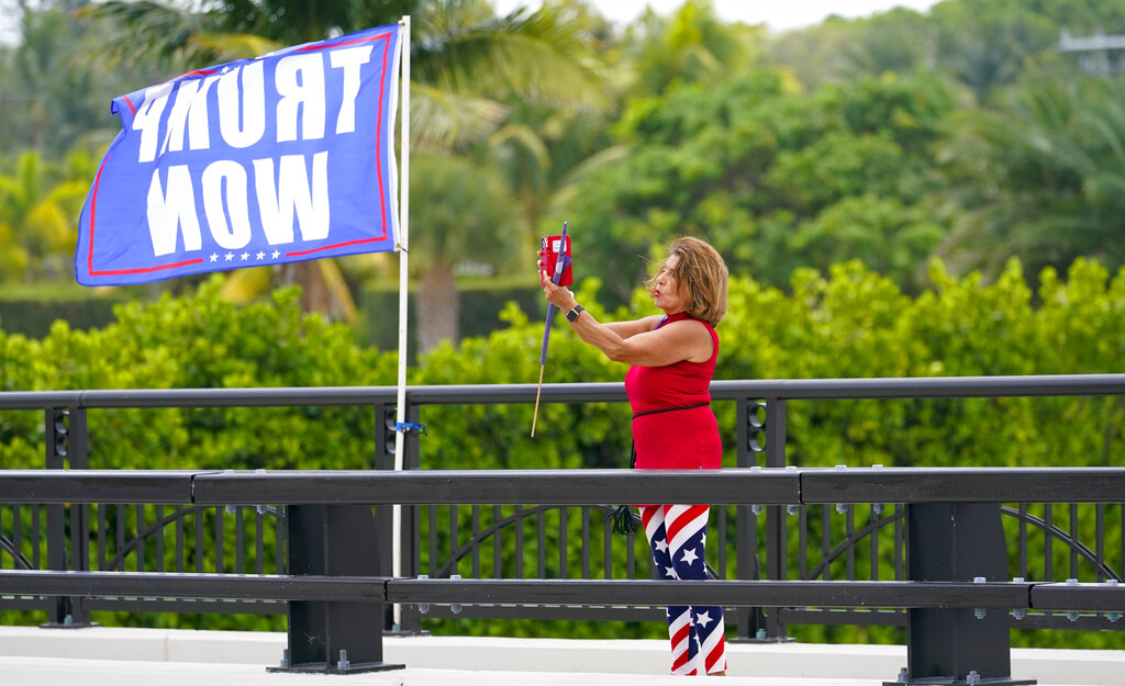 A woman stands on a bridge outside the entrance to former President Donald Trump's Mar-a-Lago estate, Tuesday, Aug. 9, 2022, in Palm Beach, Fla. The FBI searched Trump's Mar-a-Lago estate as part of an investigation into whether he took classified records from the White House to his Florida residence, people familiar with the matter said Monday. (AP Photo/Lynne Sladky)