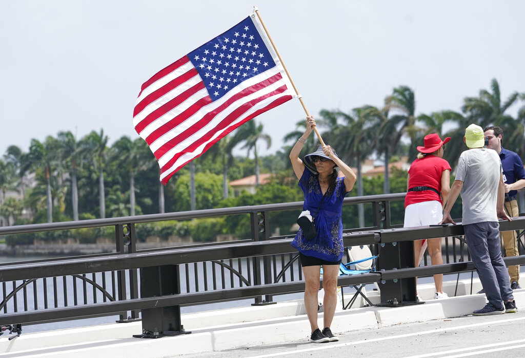Adriane Shochet stands on a bridge outside the entrance to former President Donald Trump's Mar-a-Lago estate, Tuesday, Aug. 9, 2022, in Palm Beach, Fla. The FBI searched Trump's Mar-a-Lago estate as part of an investigation into whether he took classified records from the White House to his Florida residence, people familiar with the matter said Monday. (AP Photo/Lynne Sladky)