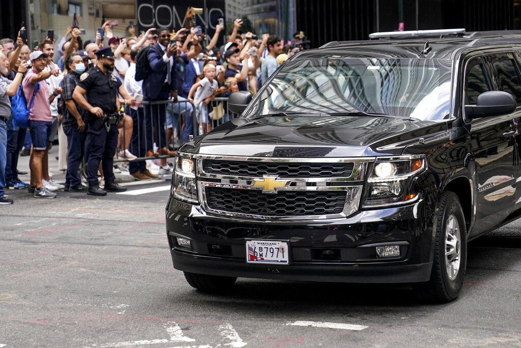 Onlookers reacts as a vehicle carrying former President Donald Trump departs 28 Liberty after depositions in a civil investigation, Wednesday, Aug. 10, 2022, in New York. Trump says he invoked the Fifth Amendment and wouldn't answer questions under oath in the long-running New York civil investigation into his business dealings. (AP Photo/John Minchillo)