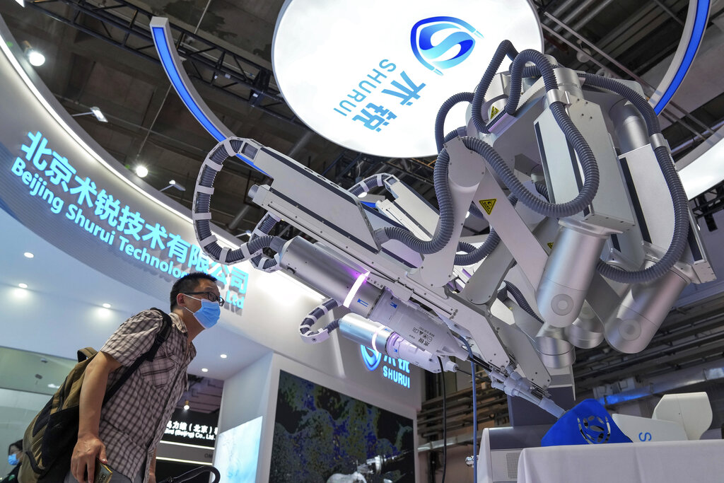 A visitor wearing a face mask takes a closer look at a Chinese-made robotic arm used for surgeon during the World Robot Conference at the Yichuang International Conference and Exhibition Centre in Beijing, Thursday, Aug. 18, 2022. (AP Photo/Andy Wong)