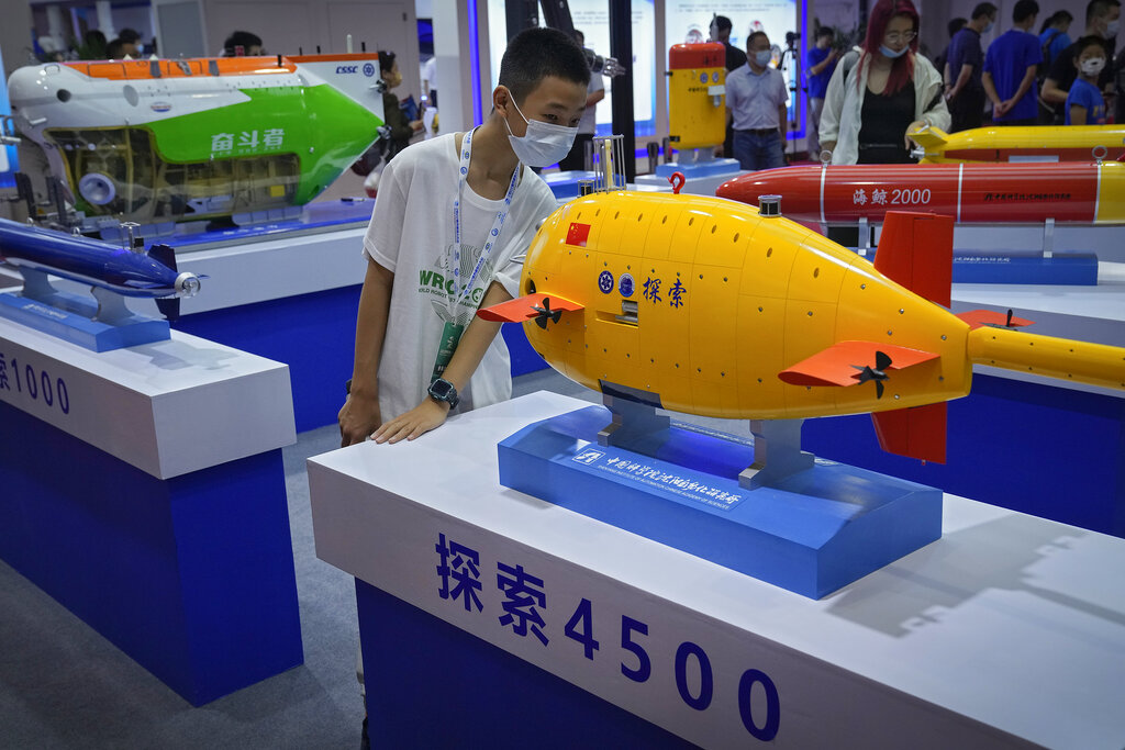 A child wearing a face mask takes a closer look at a Chinese-made unmanned submarines model on display at the World Robot Conference at the Yichuang International Conference and Exhibition Centre in Beijing, Thursday, Aug. 18, 2022. (AP Photo/Andy Wong)