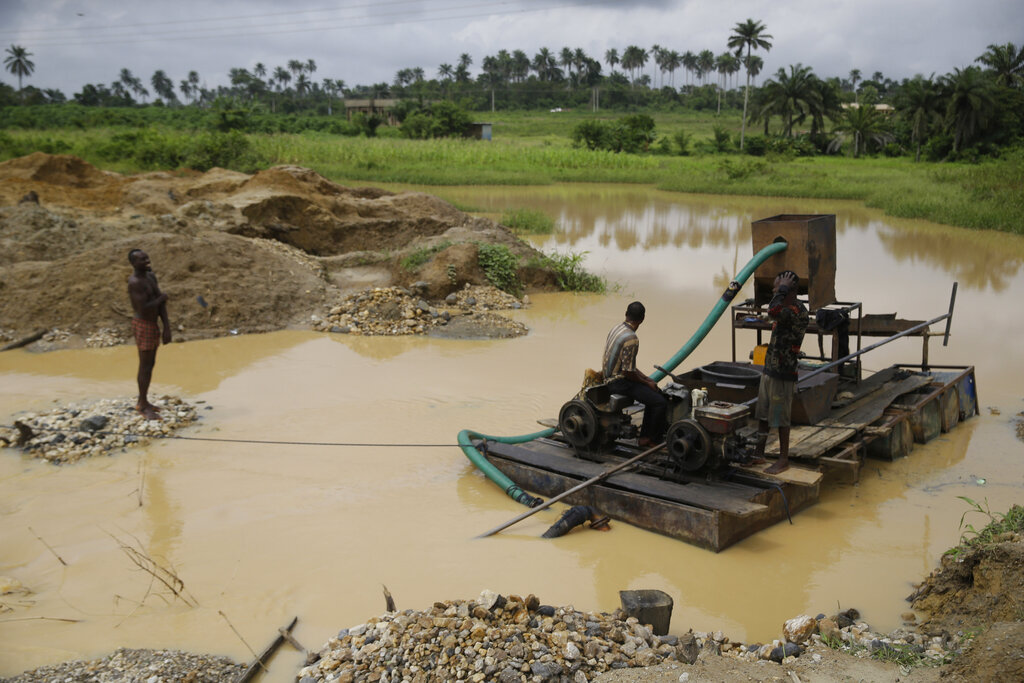 Men take a break at an illegal mining site in Osogbo, Nigeria, on Tuesday, May 31, 2022. Osunyemi Ifarinu Ifabode, the chief priest of the Osun River, says illegal mining has polluted the sacred waterway, and he advises worshippers not to drink from it. (AP Photo/Sunday Alamba)