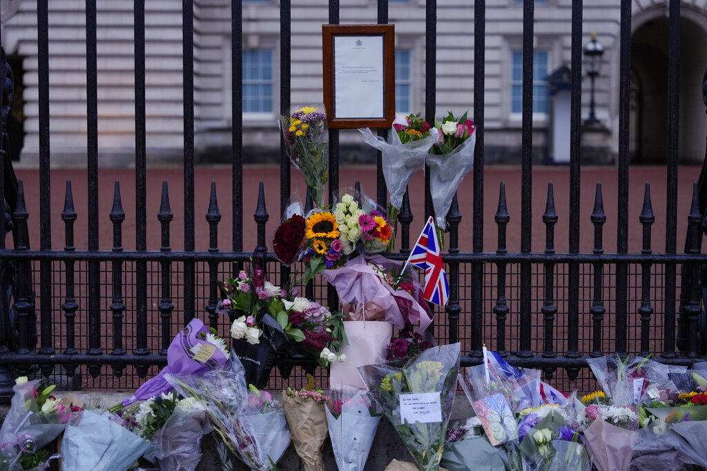 Flowers have been left next to a Buckingham Palace message announcing the death of Queen Elizabeth at the gate of the Palace in London, Friday, Sept. 9, 2022. Queen Elizabeth II, Britain's longest-reigning monarch and a rock of stability across much of a turbulent century, died Thursday Sept. 8, 2022, after 70 years on the throne. She was 96. (AP Photo/Kirsty Wigglesworth)