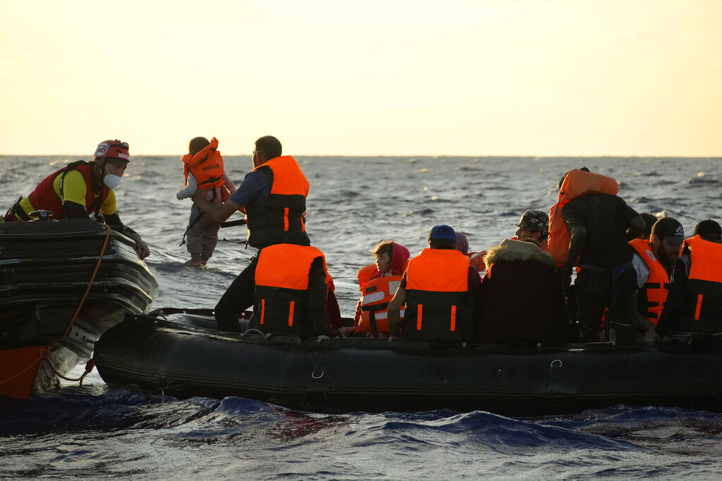 A migrant hands a baby to a lifeguard from the Spanish NGO Open Arms during a rescue operation at international waters zone of Libya SAR (Search and Rescue) in the Mediterranean sea, Thursday, Sept. 15, 2022. Migrants from Syria and Sudan, including six children, were rescued by the NGO Open Arms crew members after their boat overturned and started to sink. (AP Photo/Petros Karadjias)