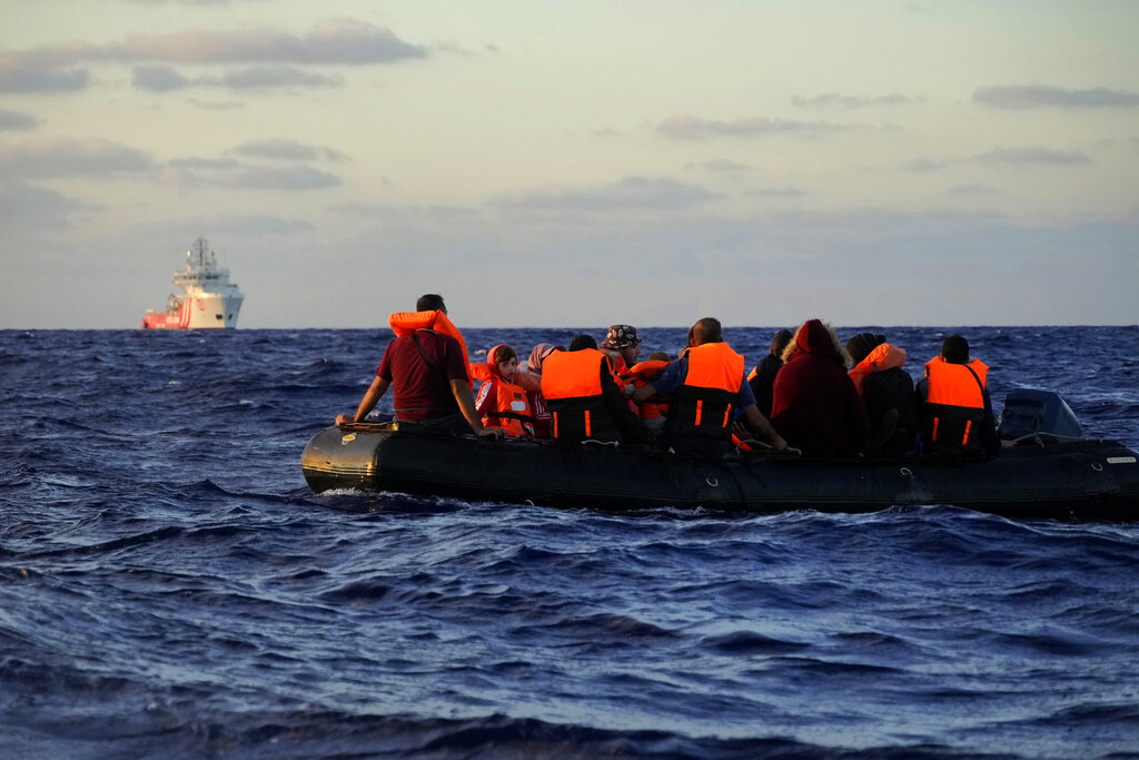 Spanish NGO Open Arms rescue ship, left, approaches a rubber boat with migrants during a rescue operation at international waters zone of Libya SAR (Search and Rescue) in the Mediterranean sea, Thursday, Sept. 15, 2022. Seventeen migrants from Syria and Sudan, including six children, were rescued by the NGO Open Arms crew members after their boat overturned and started to sink. (AP Photo/Petros Karadjias)