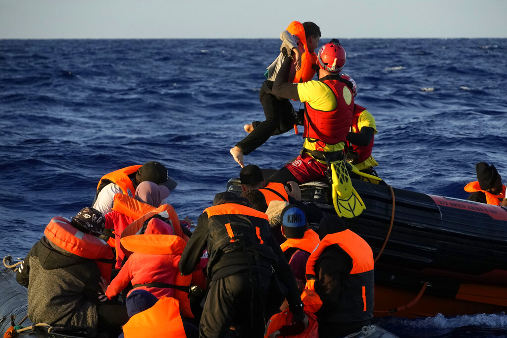 Un bagnino della ONG spagnola Open Arms aiuta un bambino e altri migranti durante un'operazione di salvataggio nella zona delle acque internazionali della Libia SAR (Search and Rescue) nel Mar Mediterraneo, giovedì 15 settembre 2022. Foto: AP/Petros Karadjias