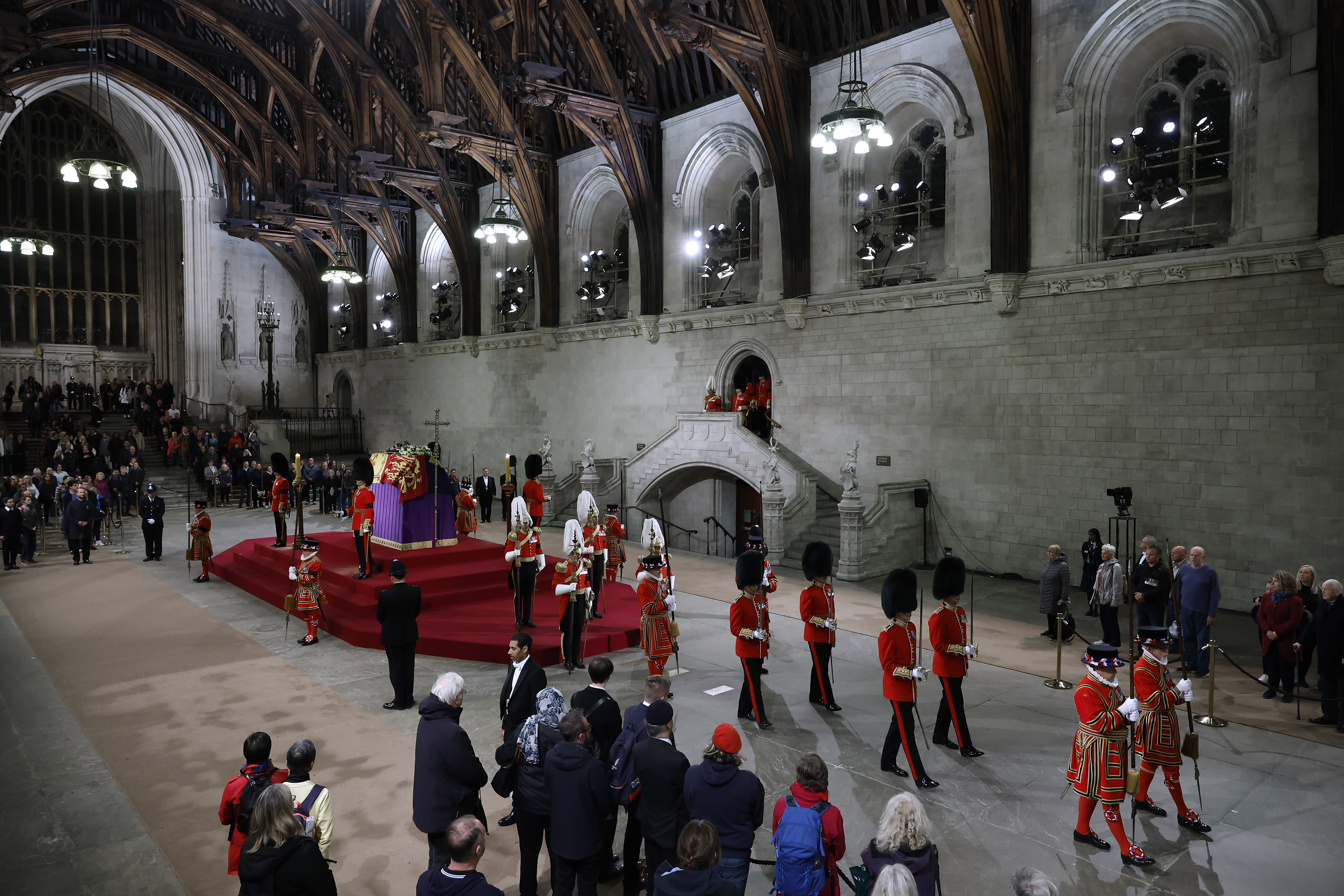 The Changing of the Guard takes place as people wait to walk past the coffin of Queen Elizabeth II as it lies in state on the catafalque in Westminster Hall, at the Palace of Westminster, London, early Saturday Sept. 17, 2022. The Queen will lie in state in Westminster Hall for four full days before her funeral on Monday Sept. 19. (Chip Somodevilla/Pool via AP)