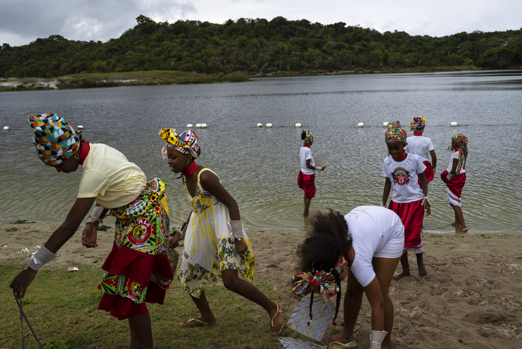 Afro Brazilian community members take part in a protest alongside the Abaete Lagoon in Salvador, Brazil, Sunday, Sept. 18, 2022. Protesters called on authorities to take action against projects that would have environmental impact on the dunes, including one to accommodate evangelical pilgrims congregating at the Abaete dune system, an area members of the Afro Brazilian faiths consider sacred. (AP Photo/Rodrigo Abd)