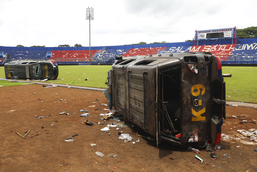 Police cars lie on their side wrecked on the pitch at Kanjuruhan Stadium in Malang, East Java, Indonesia, Sunday, Oct. 2, 2022. Panic at an Indonesian soccer match Saturday left over 100 people dead, most of whom were trampled to death after police fired tear gas to prevent violence. (AP Photo/Trisnadi)
