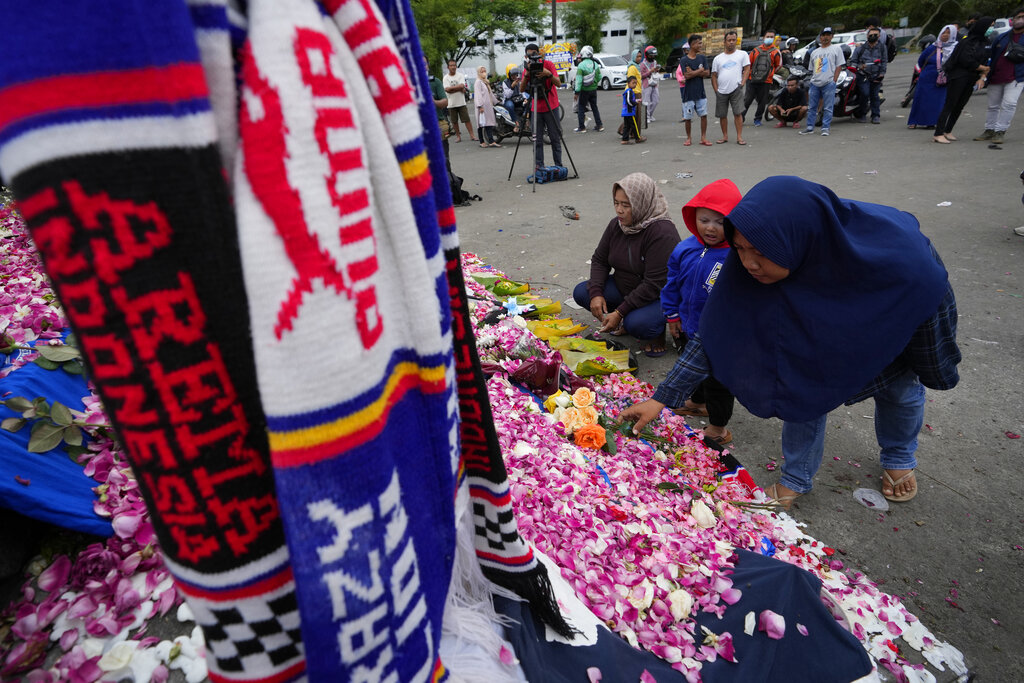 Supporters of soccer club Arema FC pray for victims of Saturday's soccer match stampede outside the Kanjuruhan Stadium in Malang, Indonesia, Monday, Oct. 3, 2022. Panic at an Indonesian soccer match Saturday left over 100 people dead, most of whom were trampled to death after police fired tear gas to stop the violence. (AP Photo/Achmad Ibrahim)