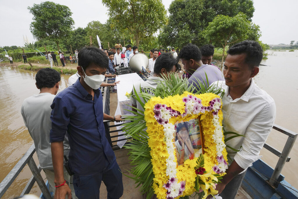 A portrait photo of a teen victim, Chanda July, is carried by her relative during her funeral procession in Koh Chamroeun village, eastern Phnom Penh, Cambodia, Friday, Oct. 14, 2022. Multiple students in southern Cambodia who were crossing a river have died after the boat they were on capsized Thursday night, officials said. (AP Photo/Heng Sinith)