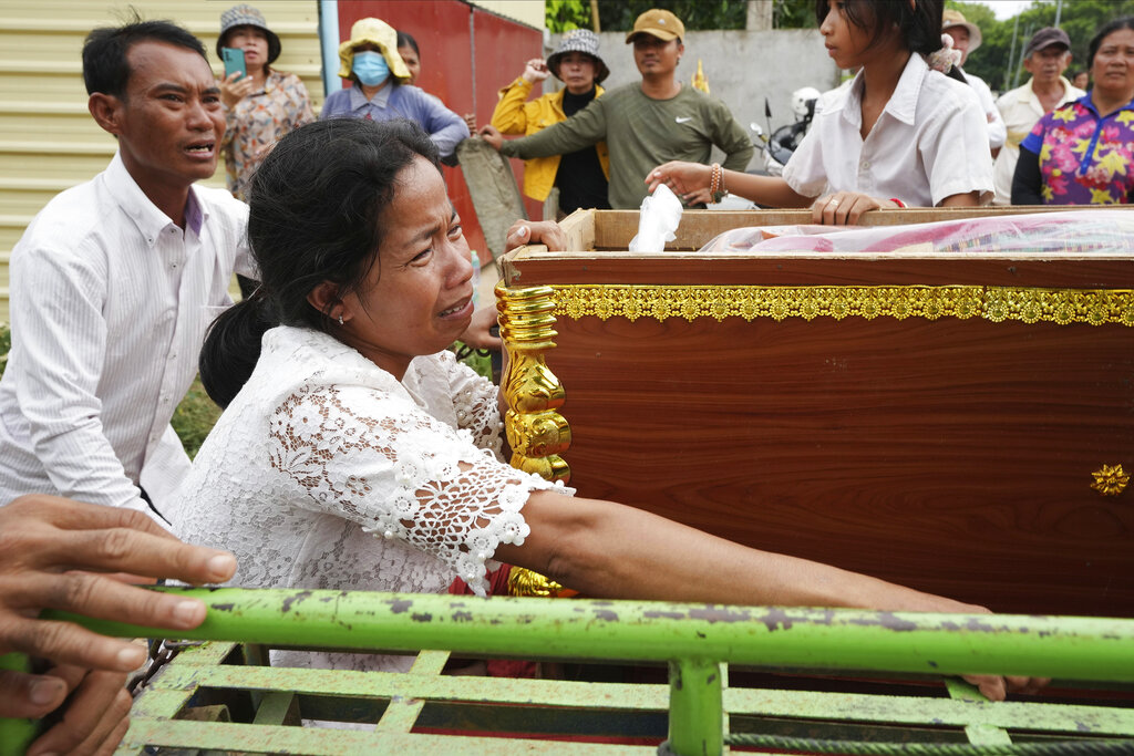 Mother of Son Sophat, a teen victim of a boat accident, cries by her daughter's coffin during a funeral procession in Koh Chamroeun village, eastern Phnom Penh, Cambodia, Friday, Oct. 14, 2022. Multiple students in southern Cambodia who were crossing a river have died after the boat they were on capsized Thursday night, officials said. (AP Photo/Heng Sinith)