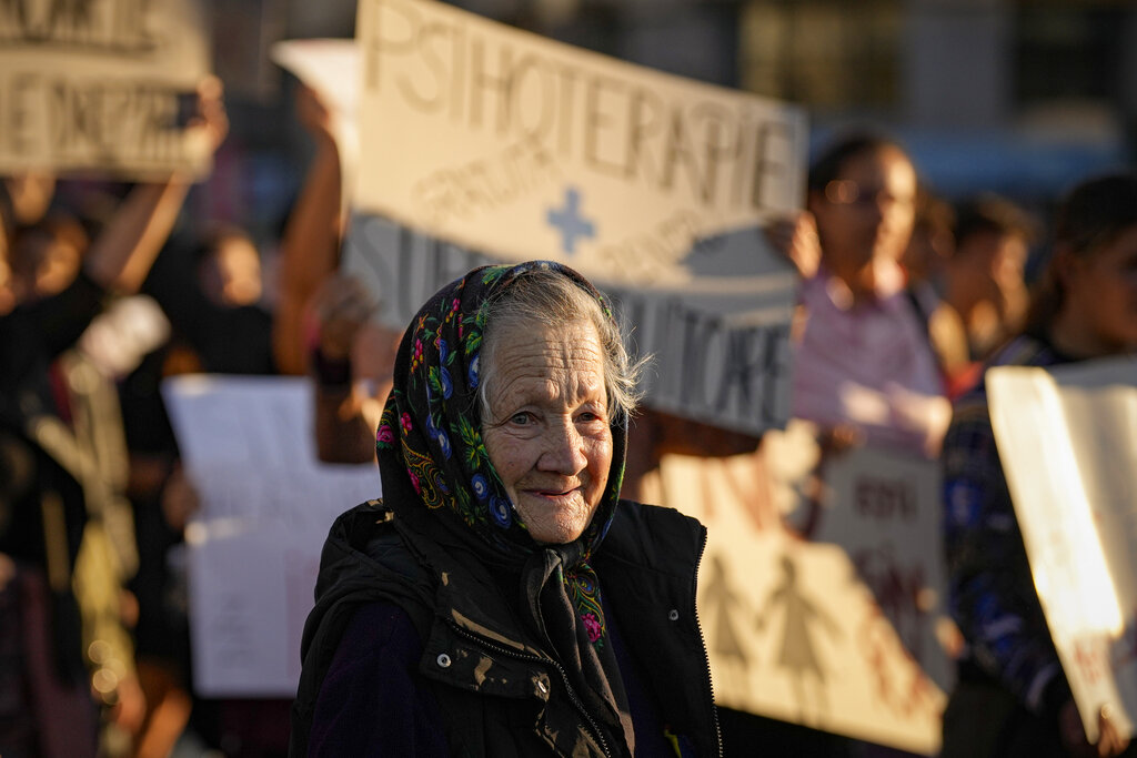 An elderly woman walks during a protest aiming to raise awareness to the violence and prejudice against women in Romanian society in Bucharest, Romania, Sunday, Oct. 23, 2022. Participants called for better support and protection for the victims of violence and the implementation of a national strategy to ensure gender equality and combat domestic violence. (AP Photo/Andreea Alexandru)