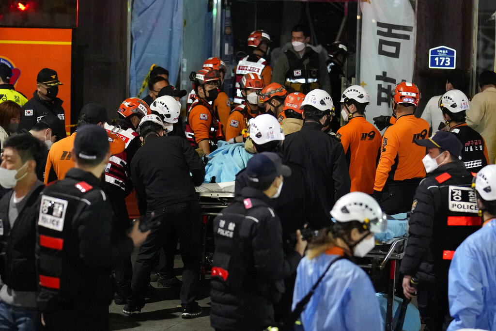 Rescue workers carry a victim on the street near the scene in Seoul, South Korea, Sunday, Oct. 30, 2022. Scores of people were killed and others were injured as they were crushed by a large crowd pushing forward on a narrow street during Halloween festivities in the capital, South Korean officials said.  (AP Photo/Lee Jin-man)