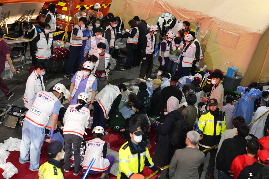 Rescue workers treat injured people on the street near the scene in Seoul, South Korea, Sunday, Oct. 30, 2022. South Korean officials say at least 120 people were killed and 100 more were injured as they were crushed by a large crowd pushing forward on a narrow street during Halloween festivities in the capital of Seoul. Choi Seong-beom, chief of Seoul’s Yongsan fire department, said the death toll could rise, saying that an unspecified number among the injured were in critical conditions. (AP Photo/Lee Jin-man)