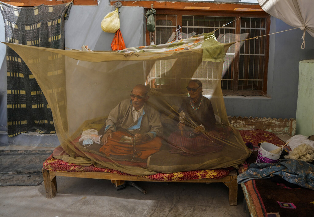 Former nomad Dawa Tundup sits inside a mosquito net along with his wife Tashi Lamo outside their home in Kharnakling village near Leh town in the cold desert region of Ladakh, India, Thursday, Sept. 15, 2022. (AP Photo/Mukhtar Khan)