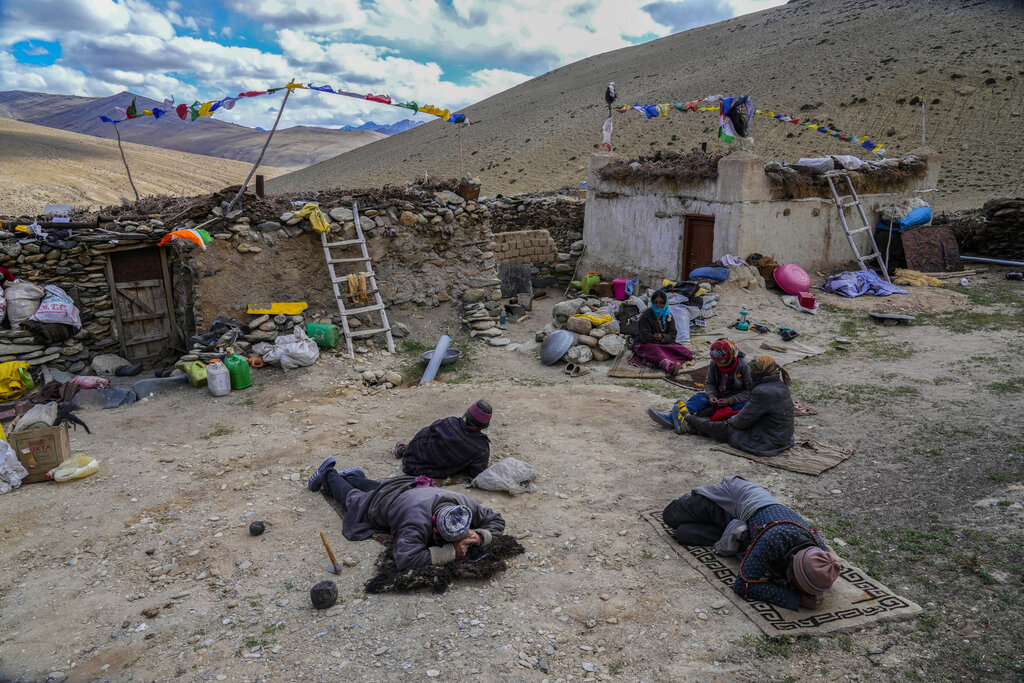 A group nomads rest as others work outside their homes on a bright sunny day in remote Kharnak village in the cold desert region of Ladakh, India, Saturday, Sept. 17, 2022. Konchok Dorjey now lives with his wife, two daughters and a son in Kharnakling, where scores of other nomadic families from his native village have also settled in the last two decades. (AP Photo/Mukhtar Khan)