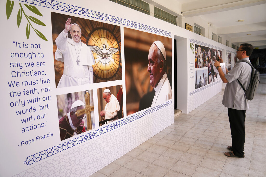 A priest takes pictures of Pope Francis posters outside the Sacred Heart Church ahead of the papal visit in Manama, Bahrain, Wednesday, Nov. 2, 2022. Pope Francis is making a November 3-6 visit to participate in a government-sponsored conference on East-West dialogue and to minister to Bahrain's tiny Catholic community, part of his effort to pursue dialogue with the Muslim world. (AP Photo/Hussein Malla)