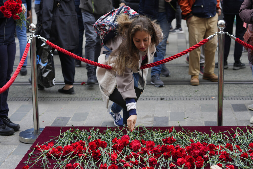 A woman leaves a flower at a memorial at the scene of Sunday's explosion on Istanbul's popular pedestrian Istiklal Avenue in Istanbul, Monday, Nov. 14, 2022. Turkey's interior minister says police have detained a suspect who is believed to have planted the bomb that exploded on a bustling pedestrian avenue in Istanbul. He said Monday that initial findings indicate that Kurdish militants were responsible for the attack. (AP Photo/Khalil Hamra)