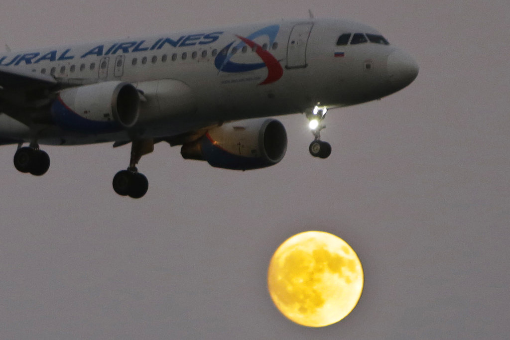 An aircraft takes position for landing at Larnaca airport as the moon rises in southern coastal city of Larnaca, Cyprus, on Wednesday, Oct. 4, 2017. (AP Photo/Petros Karadjias)