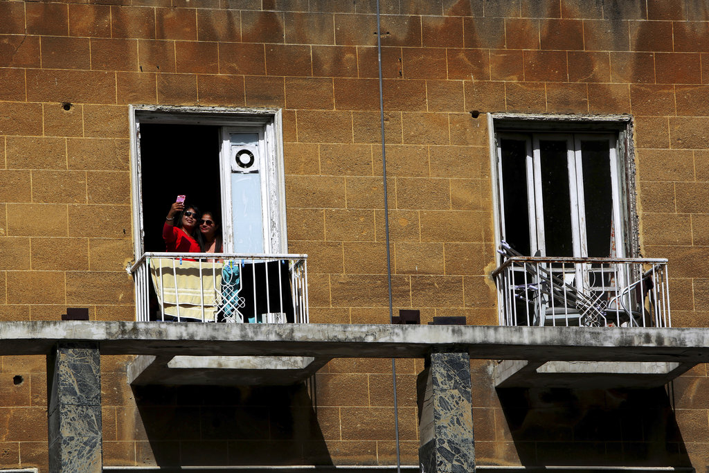Two women take a selfie from a balcony of a building in central capital Nicosia, Cyprus, on Thursday, March 1, 2018. (AP Photo/Petros Karadjias)