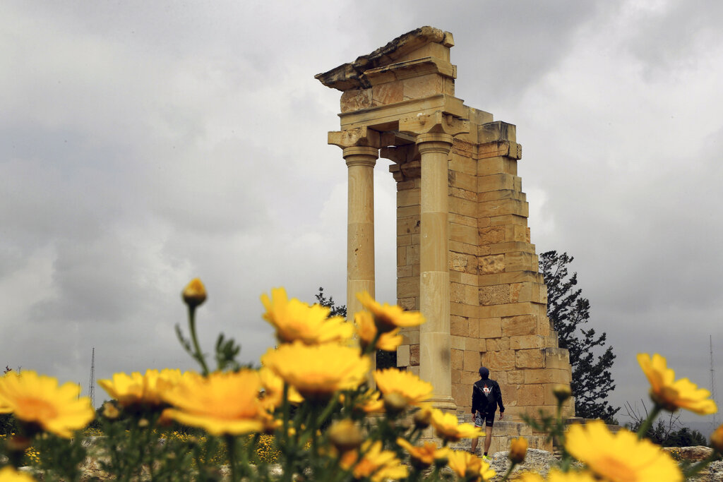 A tourist stands next to the ruins of the temple at the Sanctuary of Apollo Hylates inside the British military base area at Episkopi near coastal city of Limassol, Cyprus, Tuesday, April 9, 2019. The Sanctuary dedicated to the worship of the ancient Greek god dates as far back as the 8th century BC. (AP Photo/Petros Karadjias)