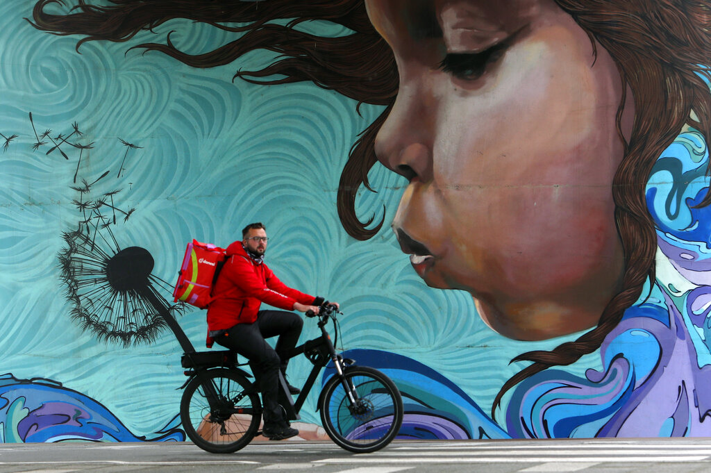 A man rides a bicycle by a graffiti under the 