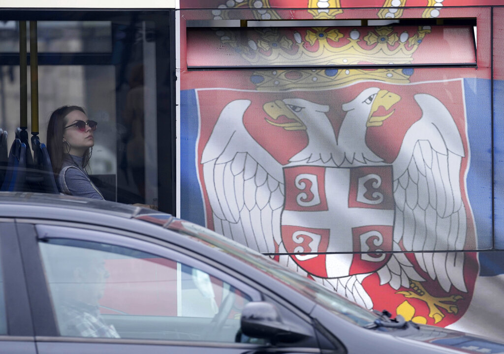 A woman looks out from a bus painted in the colours of the Serbian flag in Belgrade, Serbia, Saturday, May 28, 2022. (AP Photo/Darko Vojinovic)