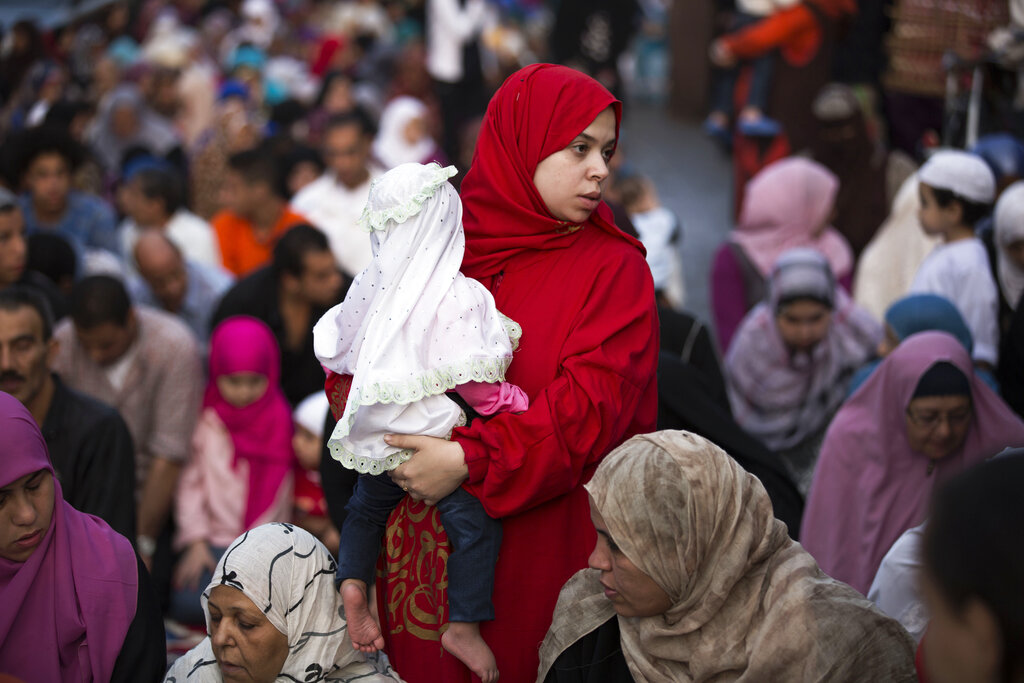 FILE - In this Tuesday, Oct. 15, 2013 file photo, an Egyptian woman prays while holding her daughter in a street on the first day of Eid al-Ahda in Cairo, Egypt. Egypts fertility rate, which has been falling since at least 1980, has risen dramatically in the last six years, said survey results released to The Associated Press, Monday, Oct. 27, 2014. The survey, conducted jointly with Egypts Ministry of Health and Population and a U.S. Agency for International Development-funded organization, said the number of births per woman has increased from 3 to 3.5 since 2008. The news raises serious economic concerns for the Arab worlds most populous country, whose economy has been staggering since its 2011 revolt. (AP Photo/Manu Brabo, File)