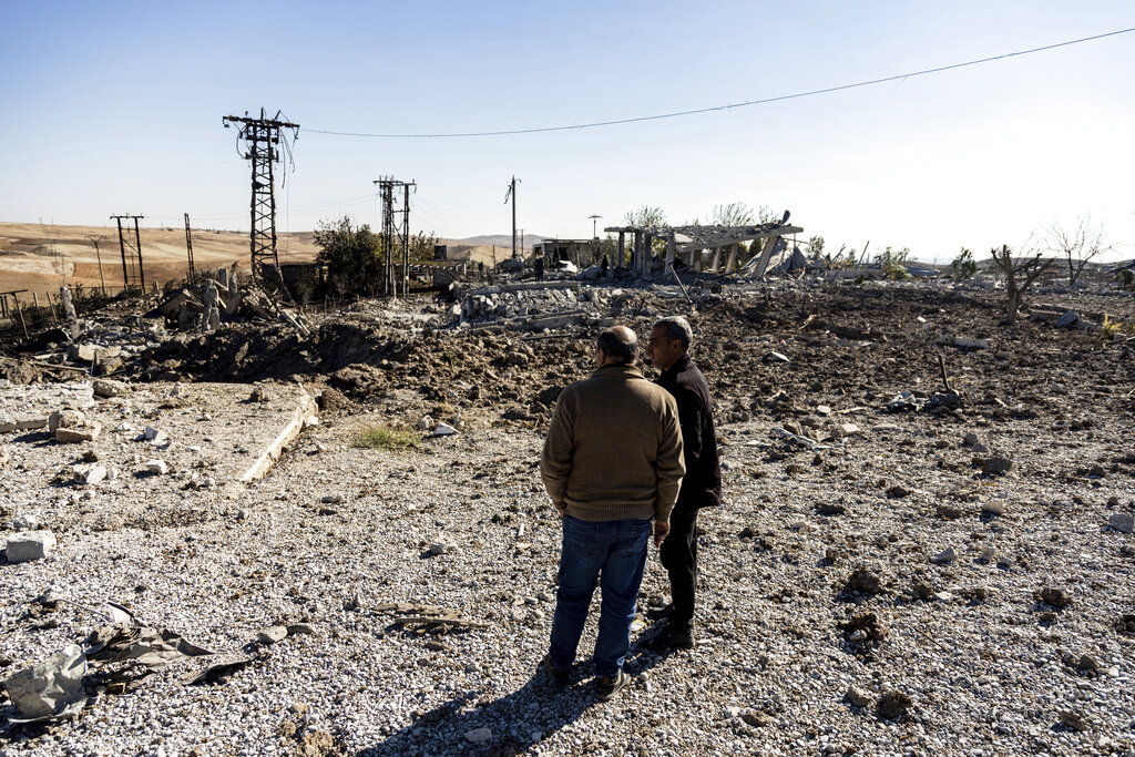 People look at a site damaged by Turkish airstrikes that hit an electricity station in the village of Taql Baql, in Hasakeh province, Syria, Sunday, Nov. 20, 2022. The Turkish Defense Ministry said Sunday that Turkey launched deadly airstrikes over northern regions of Syria and Iraq, targeting Kurdish groups that Ankara holds responsible for last week's deadly bomb attack in a bustling street in Istanbul. (AP Photo/Baderkhan Ahmad)