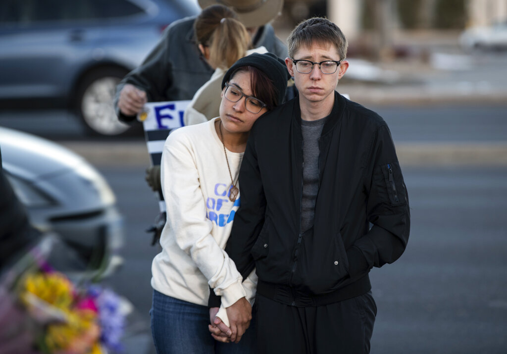 Chas Garcia, left, and Niamh Anderson, right, hold hands in front of a memorial outside of Club Q on Monday, Nov. 21, 2022, in Colorado Springs, Colo. (AP Photo/ Parker Seibold)