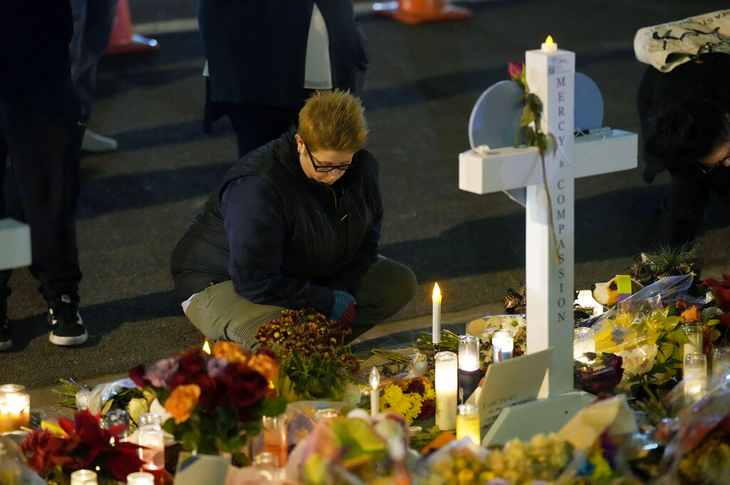 A woman kneels at a makeshift memorial near the scene of a weekend mass shooting at a gay nightclub Tuesday, Nov. 22, 2022, in Colorado Springs, Colo. (AP Photo/David Zalubowski)