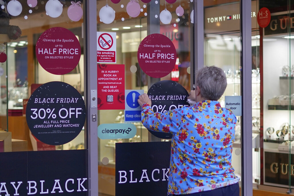 A member of staff attaches a Black Friday sign on a retail shop window in Oxford Street, in London, Friday, Nov. 25, 2022. (AP Photo/Alberto Pezzali)