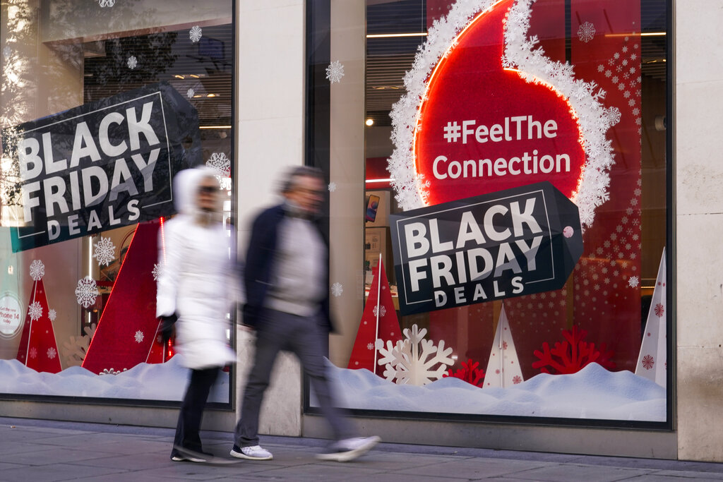 People walk past a Black Friday sign outside a retail shop in Oxford Street, in London, Friday, Nov. 25, 2022. (AP Photo/Alberto Pezzali)