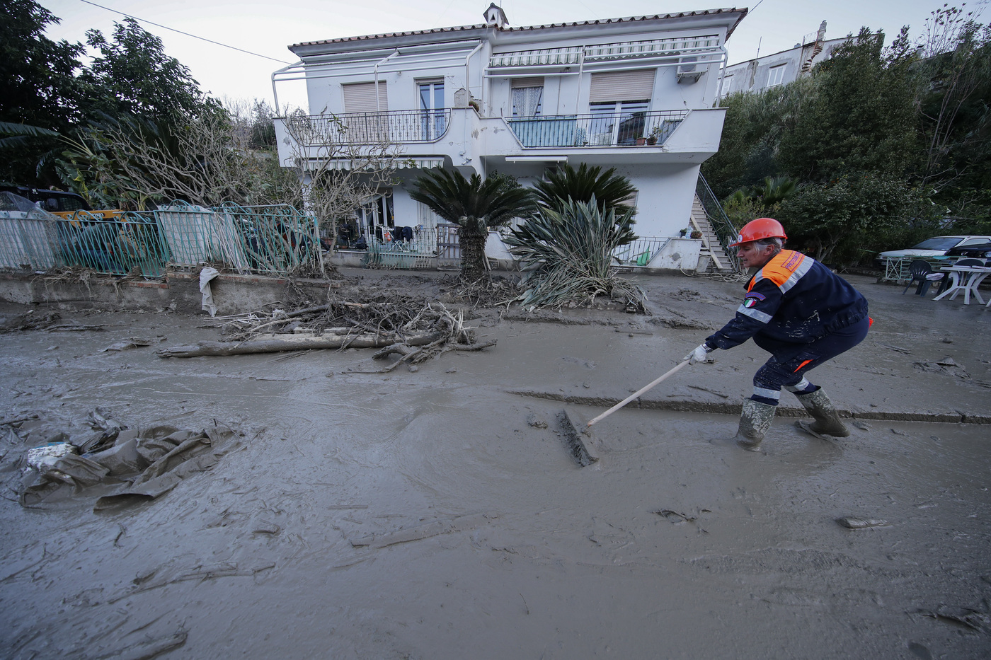 A man cleans mud and debris from a street after heavy rainfall triggered landslides that collapsed buildings and left as many as 12 people missing, in Casamicciola, on the southern Italian island of Ischia, Sunday, Nov. 27, 2022. Authorities said that the landslide that early Saturday destroyed buildings and swept parked cars into the sea left one person dead and 12 missing. (AP Photo/Salvatore Laporta)